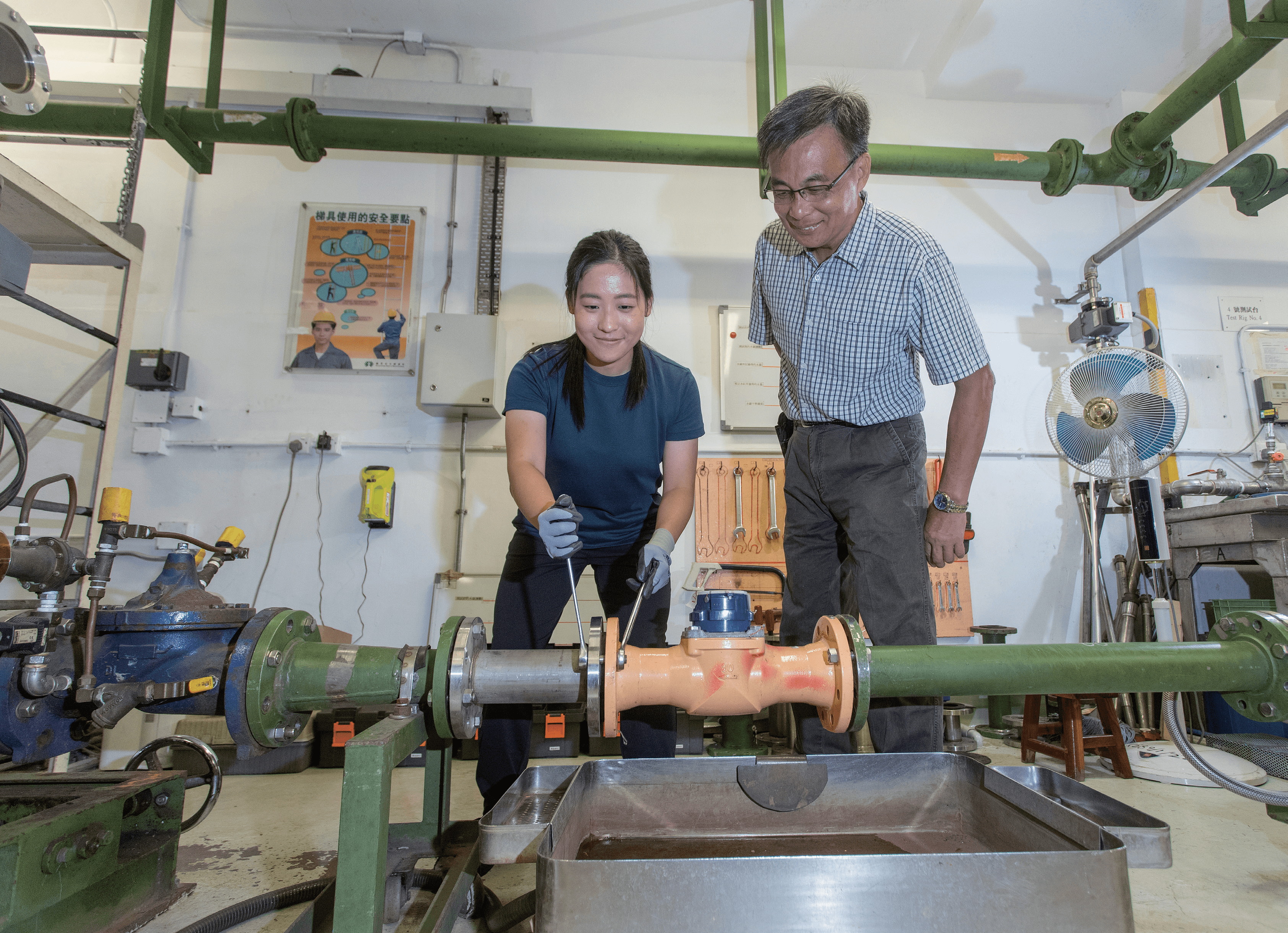 Chief Waterworks Inspector KI Tak-sun (right) instructs Koey KAO Fuk-yee, a graduate of the WSD apprentice training scheme, on how to dismantle a water meter using the correct ergonomic posture.