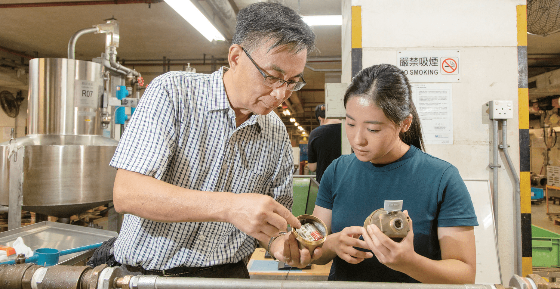 Chief Waterworks Inspector KI Tak-sun (left) shares his knowledge of water meters with Koey KAO Fuk-yee, a WSD apprentice training scheme graduate